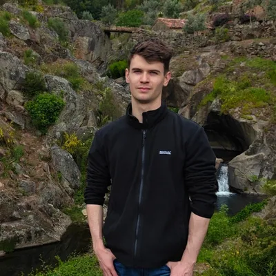 Szymon Chirowski, in een zwart fleecevest, buiten bij een rotsachtige beek.